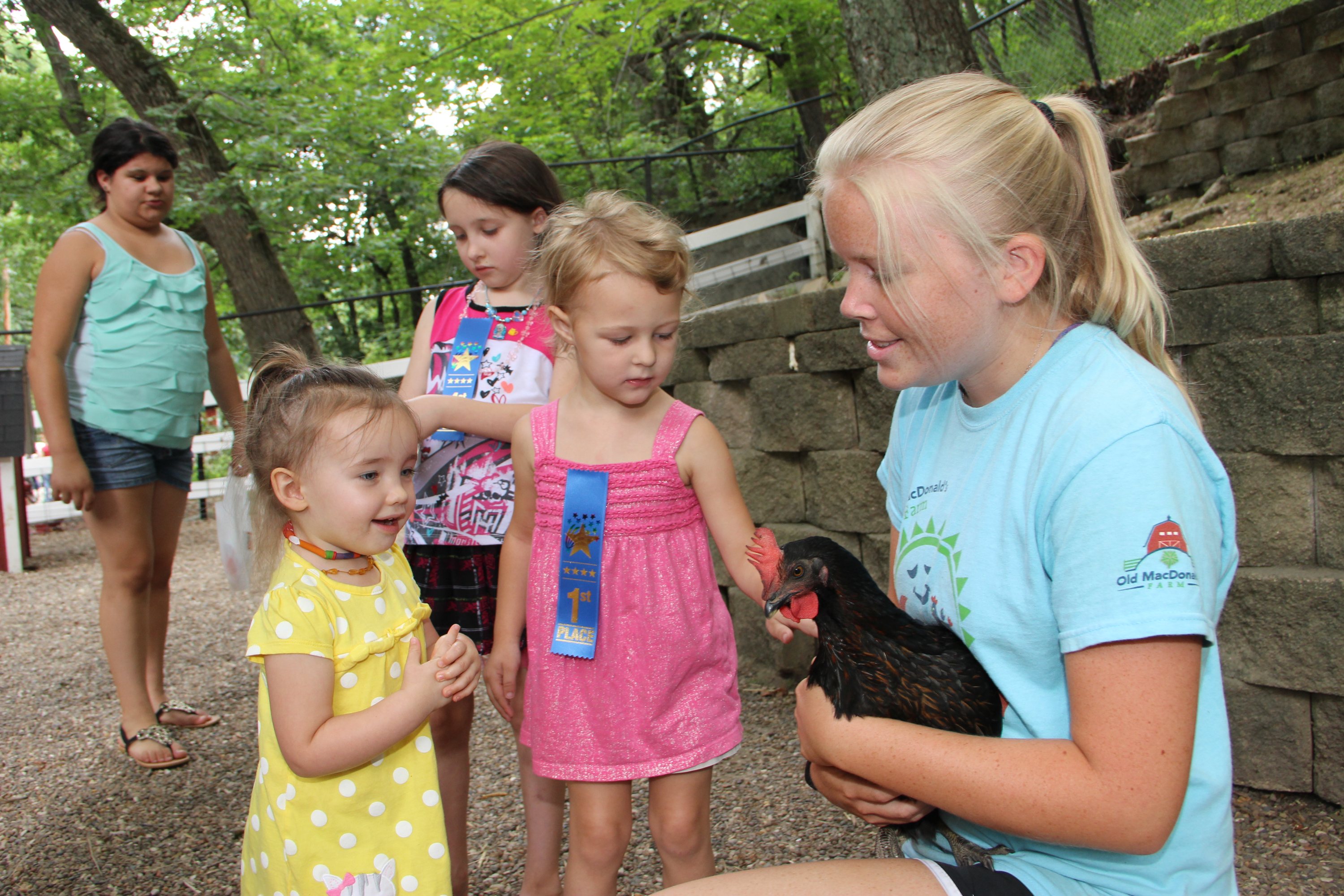 This is a picture of two children petting a rooster at Old MacDonald Farm.